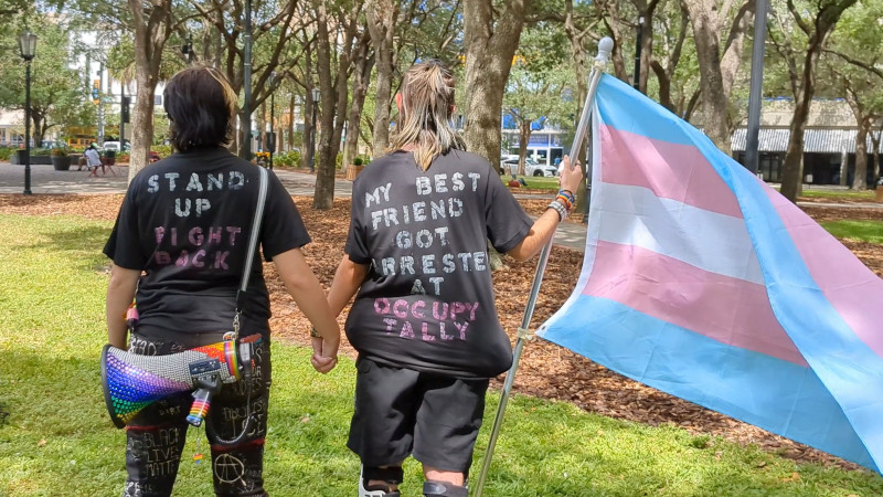 Two standing together with trans flag